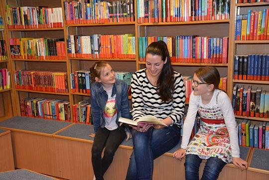 Erwachsene und zwei Kinder vor Bücherregal