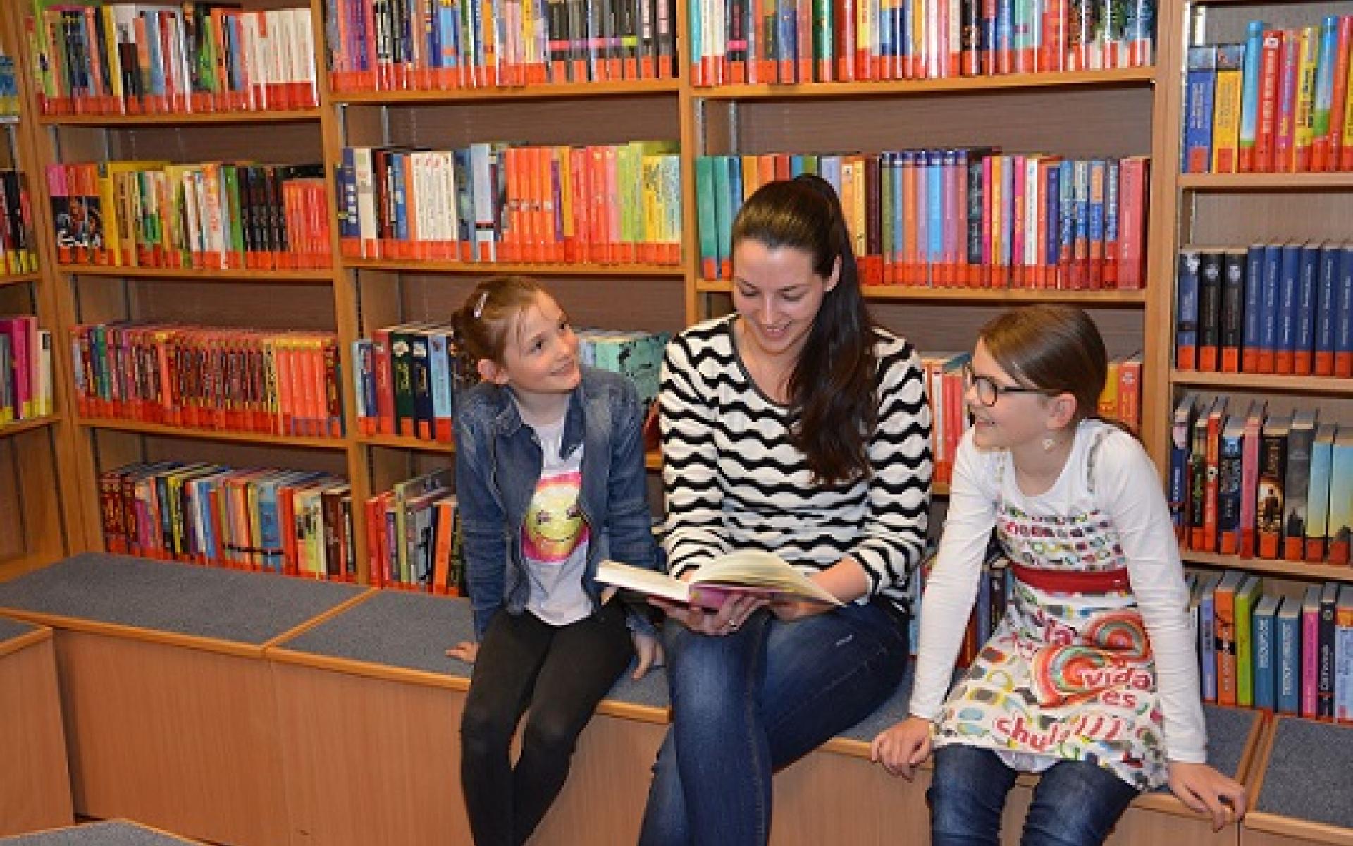 Erwachsene und zwei Kinder vor Bücherregal