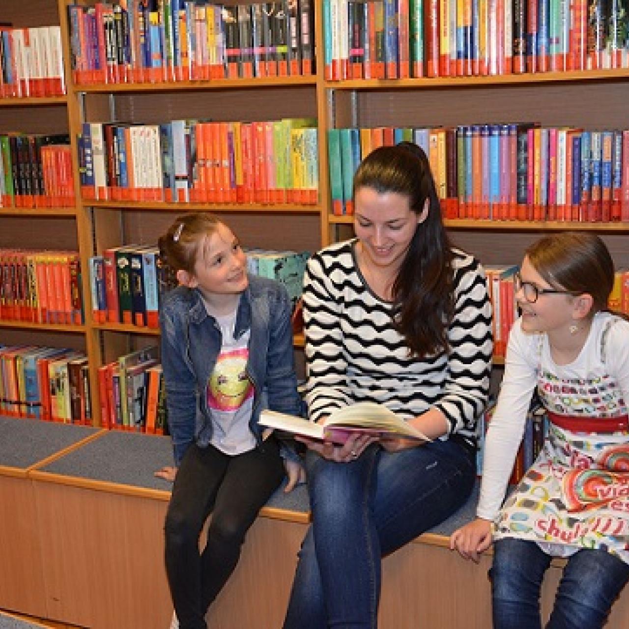 Erwachsene und zwei Kinder vor Bücherregal